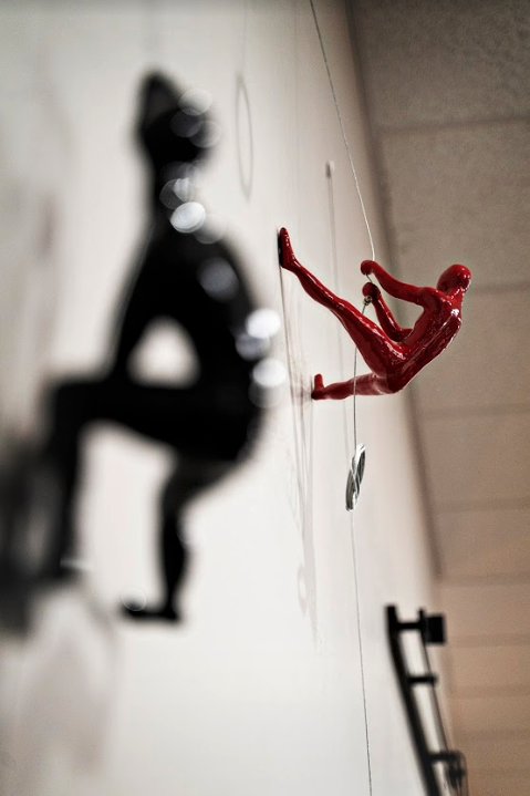 miniature sculpture of a red man climbing a wall