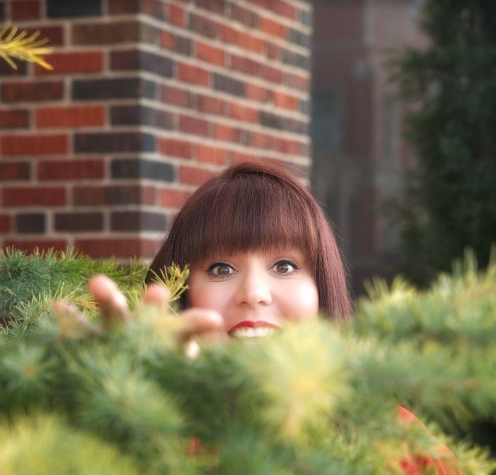 girl peeking over a bush with just most of her face visible