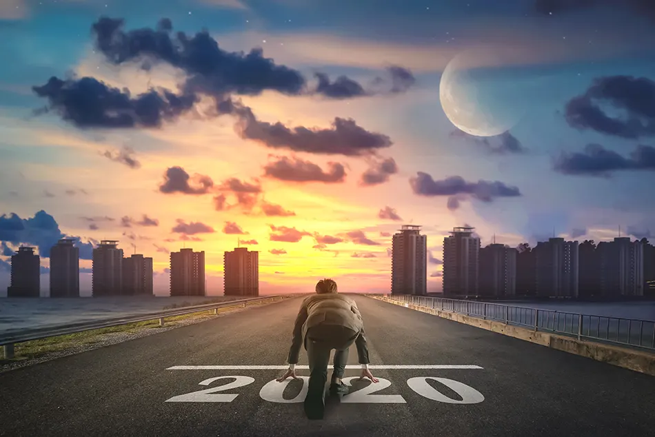 person at a 2020 starting line, looking into a sunset above a city silhouette